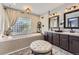 Charming bathroom featuring a deep soaking tub, a vanity with double sinks, and soft natural light at 10703 Flagler Dr, Parker, CO 80134