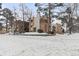 Exterior view of an apartment building with brick accents, balconies, and snow-covered grounds and bare trees at 2835 S Monaco Pkwy # 4-103, Denver, CO 80222