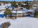 Two-story home with large deck and snowy backyard, surrounded by trees at 6017 Thunder Hill Rd, Parker, CO 80134