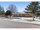 Brick ranch home with covered entryway, snowy landscaping, and mature trees at 6017 Thunder Hill Rd, Parker, CO 80134