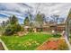 Spacious backyard featuring a green lawn, mature trees, wooden fence, and a charming seating area for outdoor enjoyment at 7861 Osceola St, Westminster, CO 80030