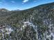 A distant aerial view of a mountain retreat nestled in a serene, snow-covered forest with mountain views at 33804 Bergen View Trl, Evergreen, CO 80439