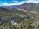 Expansive aerial view showcasing a mountain home nestled among a vast forest with views of snow capped mountains at 33804 Bergen View Trl, Evergreen, CO 80439