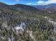 Aerial view of a cozy mountain home surrounded by a dense forest in a snowy winter landscape and mountain views at 33804 Bergen View Trl, Evergreen, CO 80439