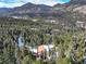 Wide aerial shot of a forest-hugged mountain home, showcasing distant snowy peaks and mountain scenery at 33804 Bergen View Trl, Evergreen, CO 80439