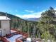 Deck view from a mountain home with expansive views of a lush forest and snow-capped mountain peaks at 33804 Bergen View Trl, Evergreen, CO 80439