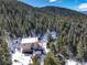 Exterior view featuring a mountain home with a red deck and roof covered in snow, surrounded by tall pine trees at 33804 Bergen View Trl, Evergreen, CO 80439