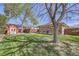 Spacious backyard with green grass, shed, mature trees, and a brick home with a red-tiled roof at 10731 Rosalie Dr, Northglenn, CO 80233