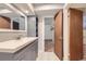 This bathroom features a gray vanity, white countertop, framed mirror, and gray shelving unit at 10731 Rosalie Dr, Northglenn, CO 80233