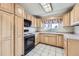 Functional kitchen with black appliances, light-toned cabinets, and tile flooring at 10731 Rosalie Dr, Northglenn, CO 80233
