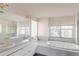Bathroom featuring double sinks, mirrors, a soaking tub and large bright windows at 116 Willowleaf Dr, Littleton, CO 80127