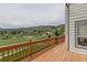 Relaxing wood deck with views of the green neighborhood, rocky landscape, and distant mountains at 116 Willowleaf Dr, Littleton, CO 80127