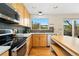 Well-lit kitchen with stainless steel appliances, light wood cabinets, stone countertops, and view to backyard at 1474 E Weldona Way, Superior, CO 80027