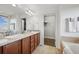 Bright bathroom with dual sinks, wood cabinets, tub, walk in closet, and tiled floors at 11594 Yellow Daisy Dr, Parker, CO 80134