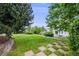 Well-manicured backyard with a lush lawn, mature trees, and a stone paver walkway leading to a seating area at 22428 Quail Run Ln, Parker, CO 80138