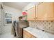 Well-lit laundry room with modern washer and dryer, storage cabinets, and utility sink at 22428 Quail Run Ln, Parker, CO 80138
