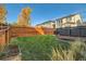 Landscaped backyard with a wooden fence, green lawn and a deck with seating at 6893 Decatur St, Denver, CO 80221