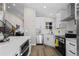 Modern kitchen featuring white cabinets, stainless steel appliances, quartz counters, and wood floors at 7431 Ames St, Arvada, CO 80003