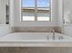 Close up of soaking tub with tile surround and chrome fixtures beneath a window at 6268 Dakota Ridge Dr, Littleton, CO 80125