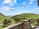 Relaxing patio featuring comfortable armchairs, a small table, and scenic views of rolling hills and blue sky at 6268 Dakota Ridge Dr, Littleton, CO 80125