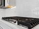Close-up of a sleek black stovetop with white backsplash, set in a modern kitchen with premium appliances at 6268 Dakota Ridge Dr, Littleton, CO 80125