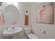 Charming powder room with pedestal sink, oval mirror, and stylish wall art at 4732 Windmill Dr, Brighton, CO 80601