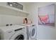 Well-lit laundry room featuring a Whirlpool washer and dryer, shelving, and stylish decor at 4732 Windmill Dr, Brighton, CO 80601