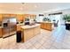 Open kitchen showcasing light wood cabinetry, a stainless steel refrigerator, island cooktop, and adjacent dining area with sliding door at 412 E 131St Ave, Thornton, CO 80241