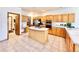 Spacious kitchen featuring light wood cabinetry, stainless steel appliances, a center island with cooktop, and tiled floors at 412 E 131St Ave, Thornton, CO 80241