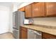 A refrigerator and dishwasher in a kitchen with wood cabinets and granite counters at 7373 E Iowa Ave # 1124, Denver, CO 80231