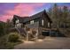 Beautiful mountain home with stone accents, black siding, and a built-in garage, accented by a colorful sky at 239 Aspen Pl, Evergreen, CO 80439