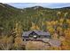 View of a sprawling single-Gathering home with a wooded backdrop, and prominent deck at 239 Aspen Pl, Evergreen, CO 80439