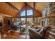 Spacious living room with hardwood floors, stone fireplace, vaulted ceilings, and large windows with mountain views at 239 Aspen Pl, Evergreen, CO 80439