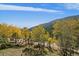 Picturesque view of golden aspen trees and a distant mountain range under a sunny, cloud-streaked sky at 239 Aspen Pl, Evergreen, CO 80439