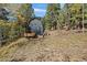 Backyard shed nestled among mature trees, with a small trailer and wood pile at 239 Aspen Pl, Evergreen, CO 80439