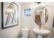 Stylish half bathroom with a pedestal sink, decorative mirror, and framed artwork at 2036 S Holly St # 1, Denver, CO 80222