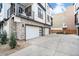 Modern townhome showcasing garages, stone accents, and balconies, situated on a paved driveway at 2036 S Holly St # 1, Denver, CO 80222