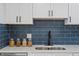 Close-up of modern kitchen sink with sleek faucet, quarts countertop, and navy subway tile backsplash at 7830 Ladore St, Commerce City, CO 80022