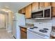 Kitchen featuring white appliances, granite countertops, wooden cabinetry, and light gray flooring at 9837 E Peakview Ave # 7, Englewood, CO 80111