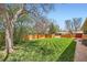 Well-maintained backyard with lush green lawn, a beautiful tree, and a wooden fence at 6773 E Baker Pl, Denver, CO 80224