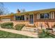 Charming brick home featuring a manicured lawn, mature shrubs, and a welcoming entrance on a sunny day at 6773 E Baker Pl, Denver, CO 80224