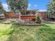 Expansive backyard with a large brick home, covered patio, and lush landscaping, perfect for outdoor living at 7105 Dover Way, Arvada, CO 80004