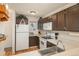 Compact kitchen featuring white appliances, dark cabinets and laminate countertops at 3506 S Depew St # 3, Denver, CO 80235
