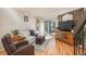 Well-lit living room with hardwood floors, sliding glass doors, and a stone feature wall enhancing its character at 3506 S Depew St # 3, Denver, CO 80235