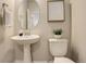 Modern powder room with pedestal sink, toilet, and oval mirror at 6727 Canosa St, Denver, CO 80221