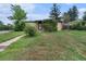 Charming brick home featuring a well-maintained front yard with mature trees and a walkway at 588 Empire St, Aurora, CO 80010