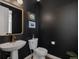 Stylish powder room with striking black walls, gold fixtures, and a sleek pedestal sink, creating a modern aesthetic at 221 Felicity Loop, Castle Rock, CO 80109