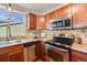 Well-equipped kitchen featuring stainless steel appliances, tile backsplash, and wood cabinetry for storage at 8408 Wild Alfalfa Pl, Parker, CO 80134