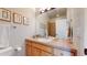 Well-lit bathroom featuring a single sink vanity, a large mirror, and a shower with neutral tile at 5398 S Jay Dr, Littleton, CO 80123