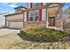 Close-up of the front of a two-story home showcasing its manicured lawn and beautiful maroon shutters at 1533 Bellflower Dr, Brighton, CO 80601